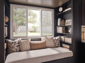 A three-lite sliding window over a couch in a cozy nook.